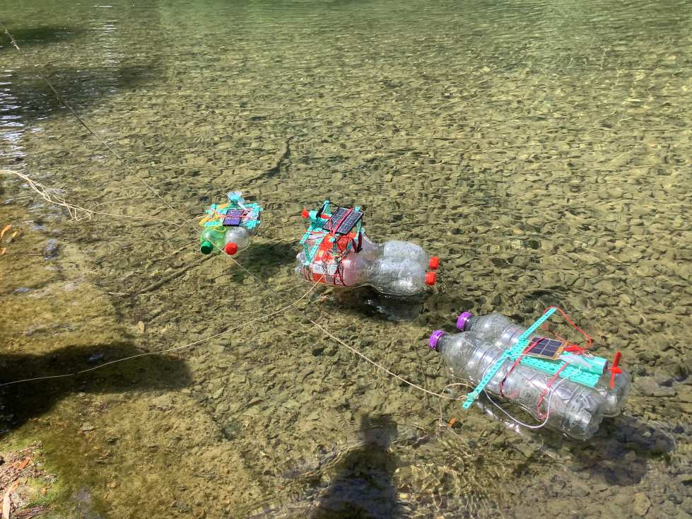 Mehrere schwimmende Boote aus Plastikflaschen sind auf einem klaren Fluss.