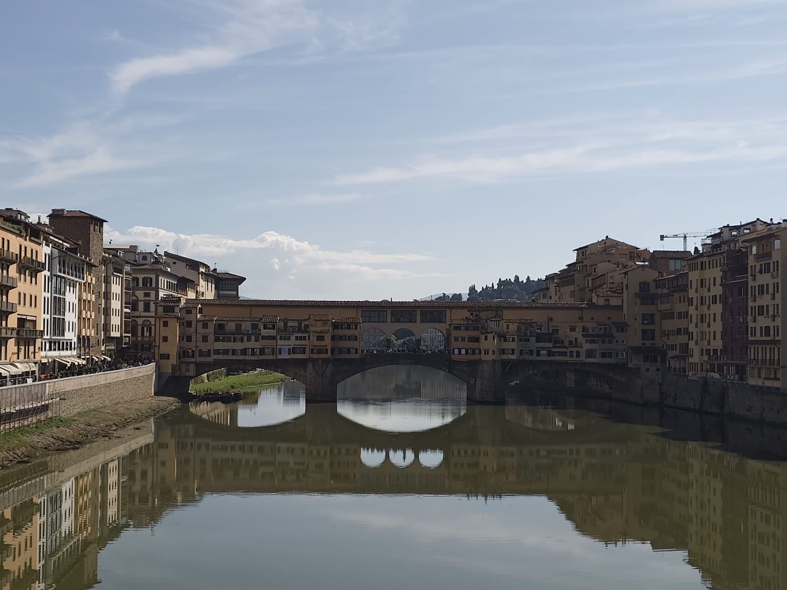 Die berühmte Ponte Vecchio in Florenz spannt sich gelb und braun über den ruhigen Fluss