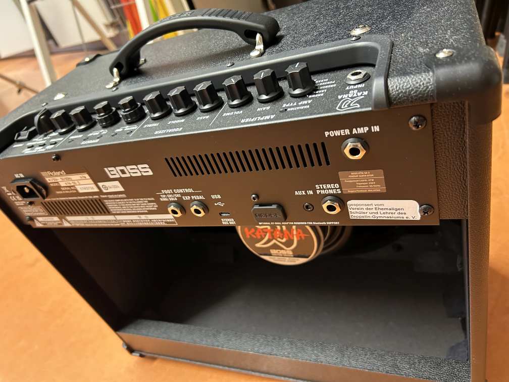 Schwarzer E Gitarrenverstärker mit sichtbaren Reglern und offenem Bereich hinten