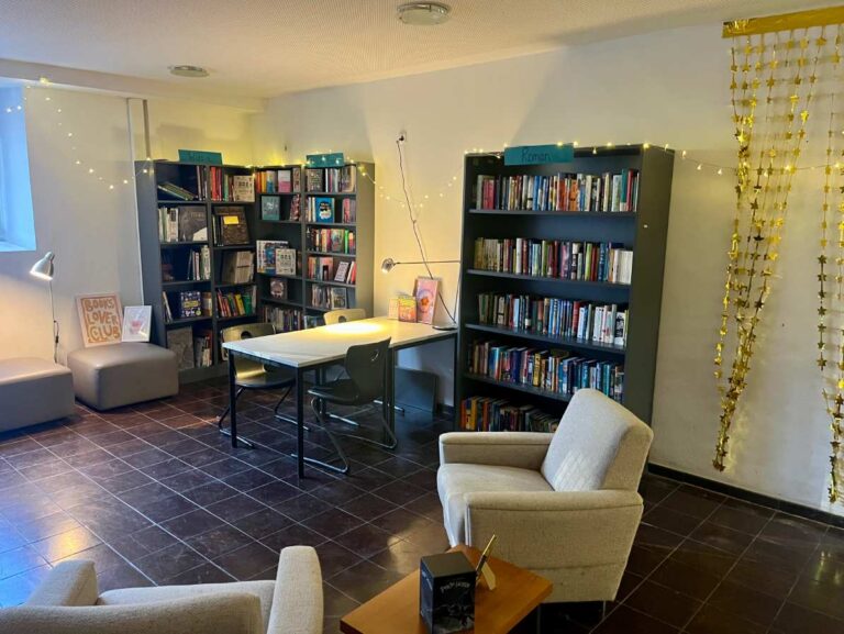 Gemütlicher Leseraum mit Bücherregalen, bequemen Sesseln und warmen Lichterketten