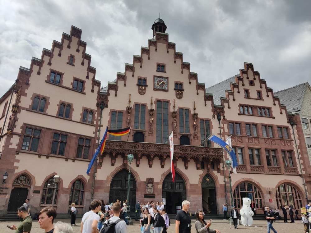 Menschen stehen vor dem alten Fachwerkgebäude mit deutschen Flaggen und grauem Himmel