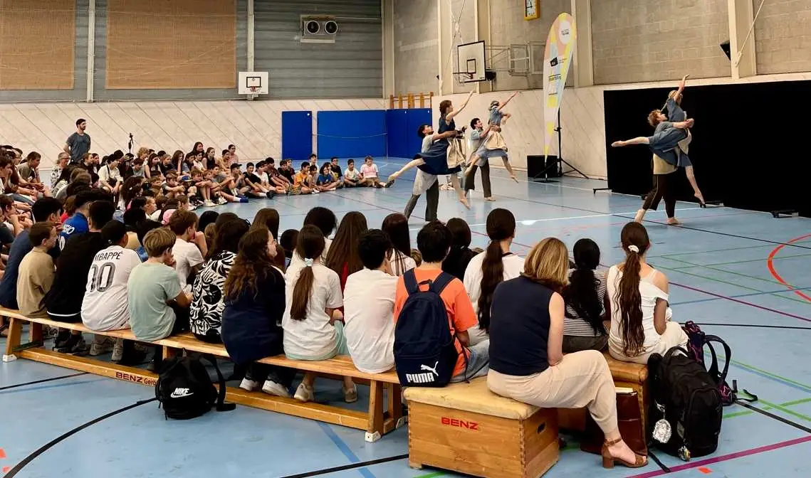 Junge Tänzerinnen wirken konzentriert in blauer Halle vor Publikum in Bunt