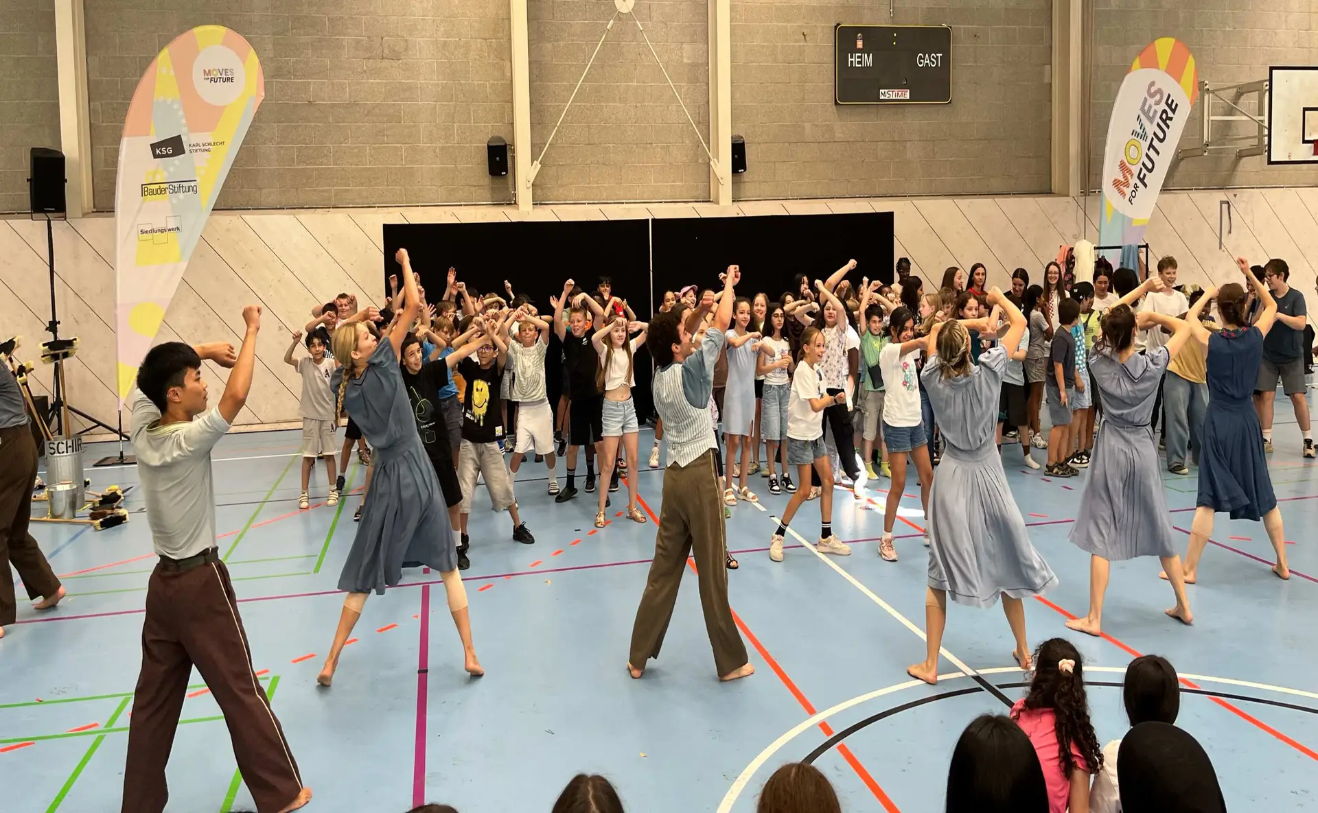 Jubelnde Gruppe in Turnhalle in bunten Farben mit Fahnen und Bühne
